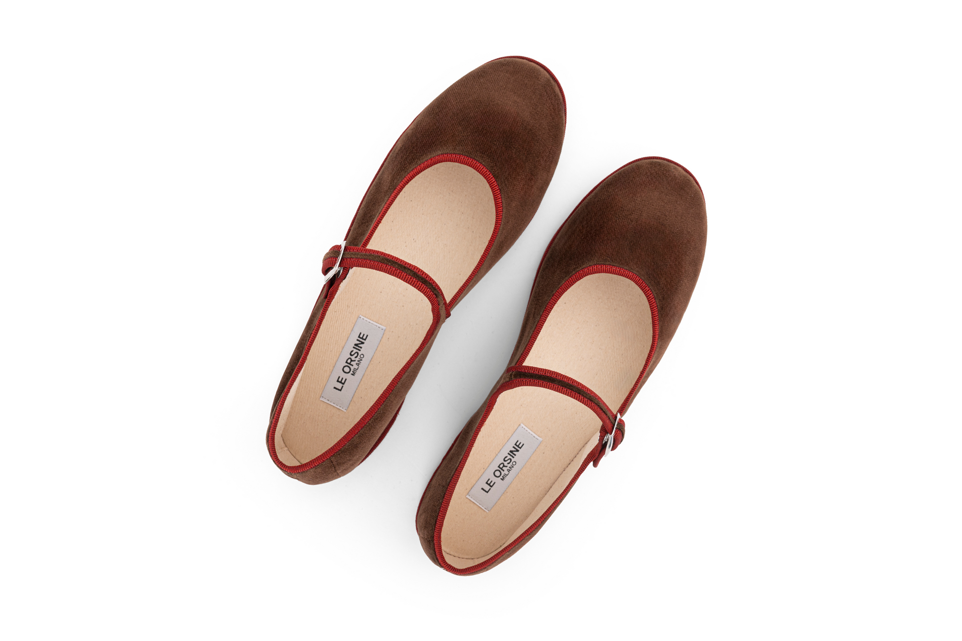A brown velvet slipper with a Maryjane style closure and a flat sole.