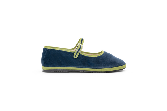 A navy and green velvet slipper shoe with a Maryjane style strap and flat sole.