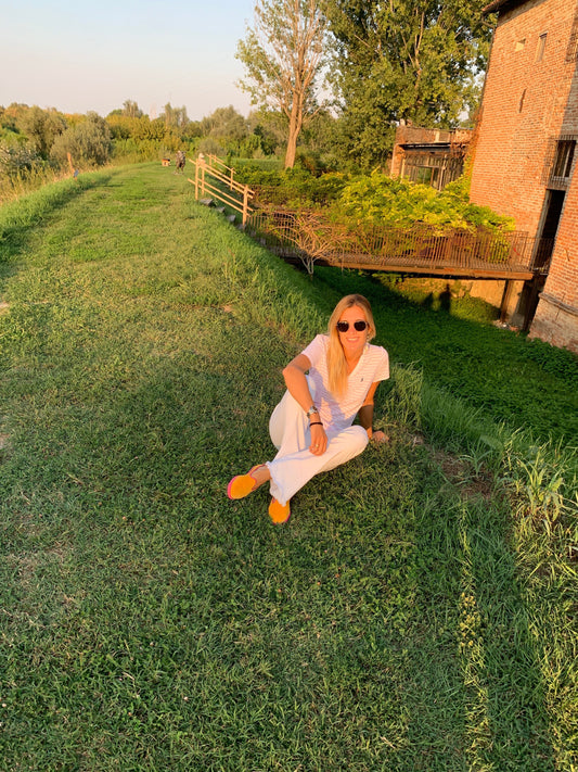 A woman sitting on grassy land in the Parma Countryside during sunset, enjoying the serene nature.