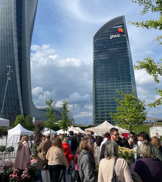 Crowd at FLORA et DECORA 22 event with modern buildings in the background and vibrant flowers on display.