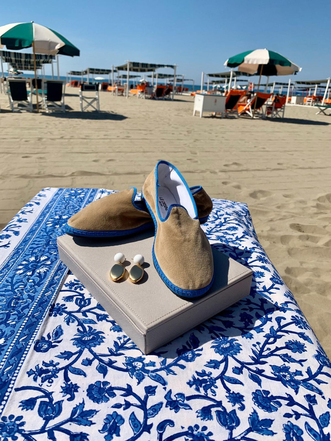 Travel: Experience Forte Dei Marmi as a Local with stylish shoes and accessories on a beach blanket.